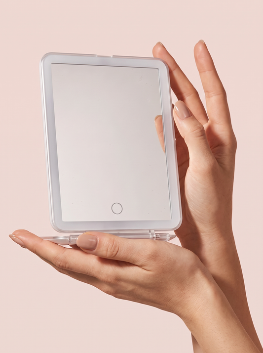 Lighted makeup mirror reflecting blurred cosmetics on a vanity surface, with LED ring visible.