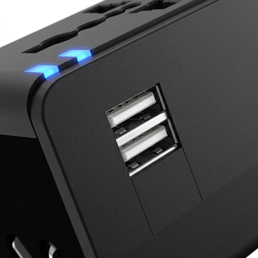 Flat lay of universal travel adapter and a coiled USB cable on a desk, with laptop and passport.